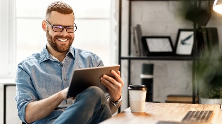 Man Smiling Viewing Tablet Device