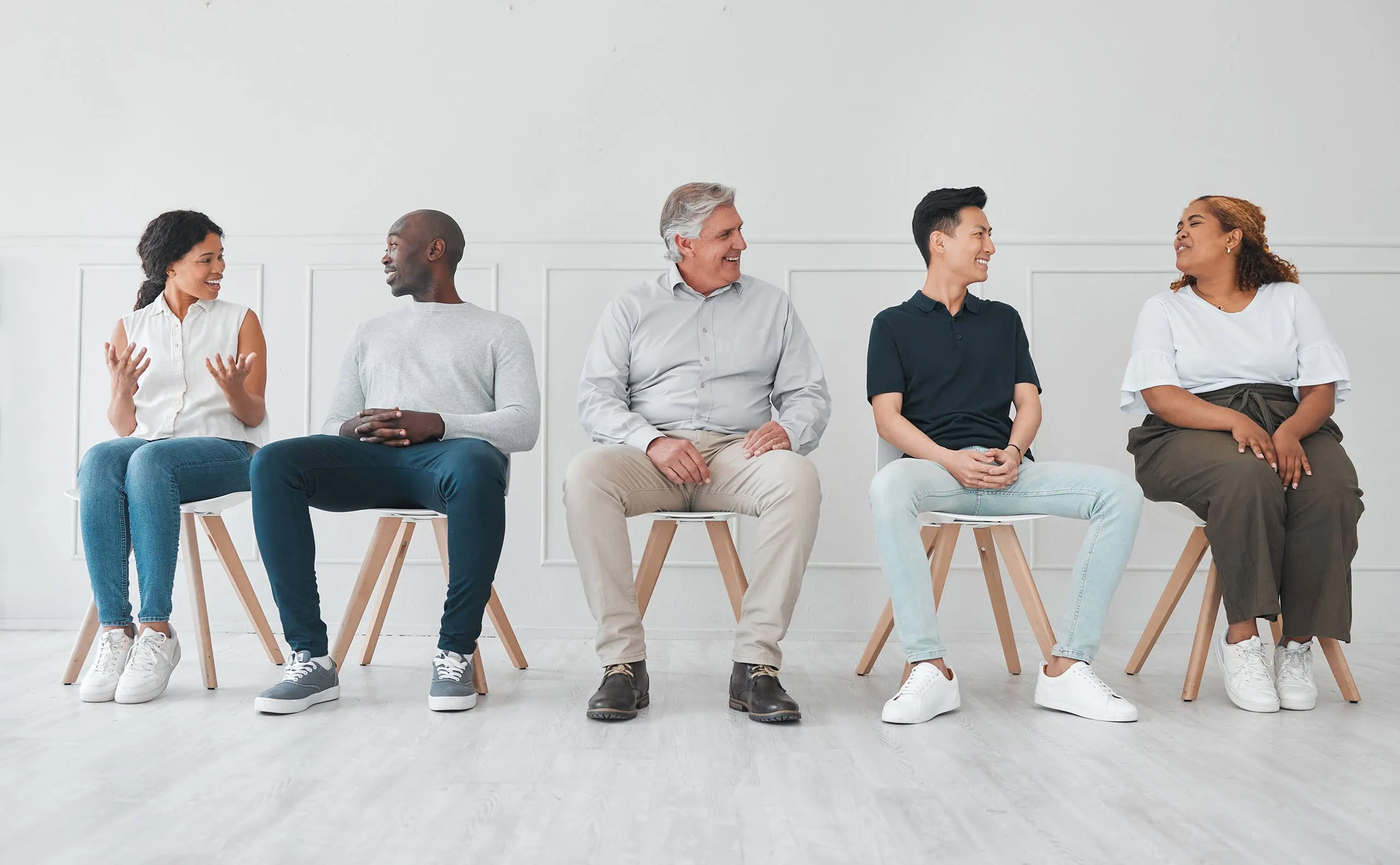Group of five adults seated in a row conversing